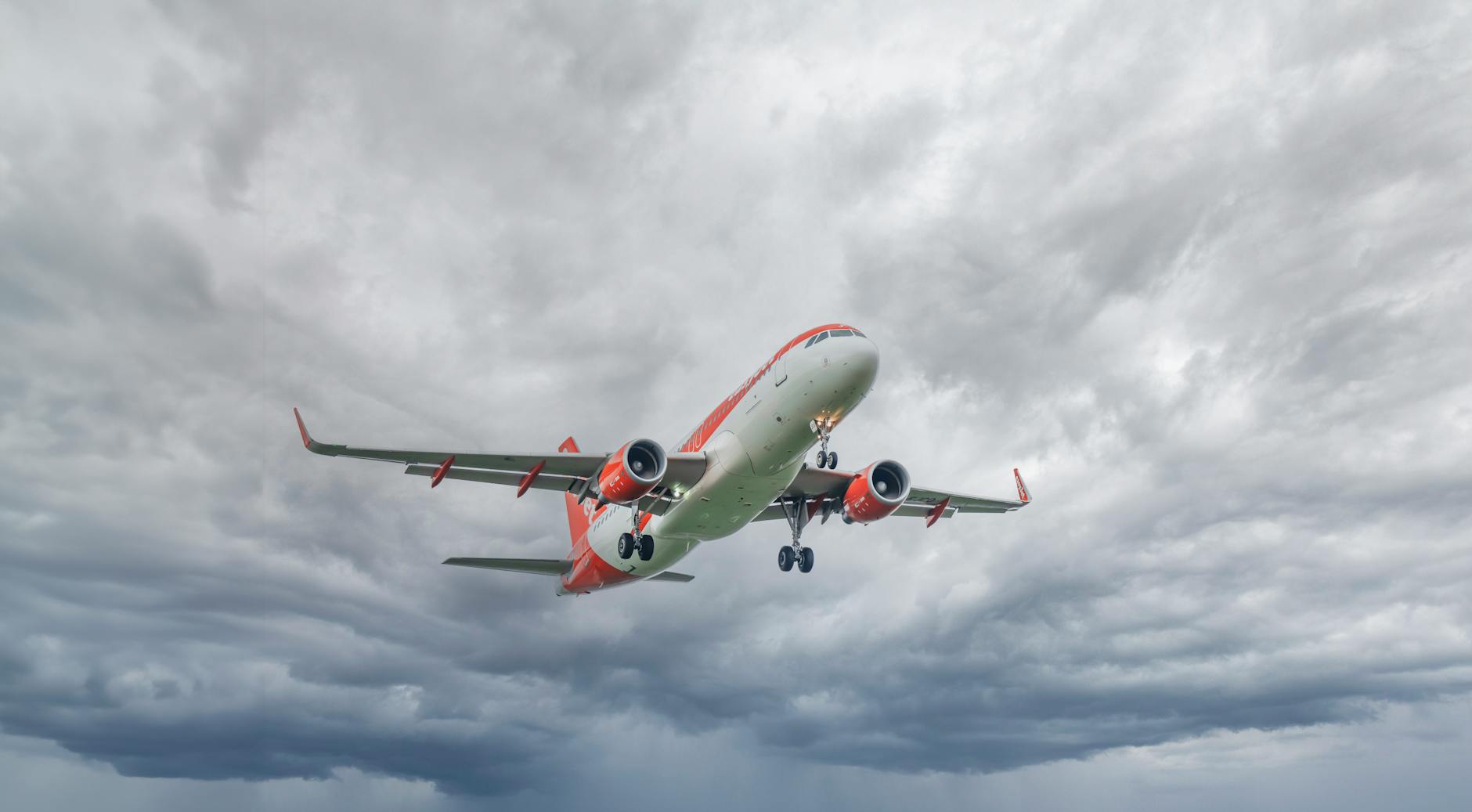 a commercial airplane flying against a cloudy sky