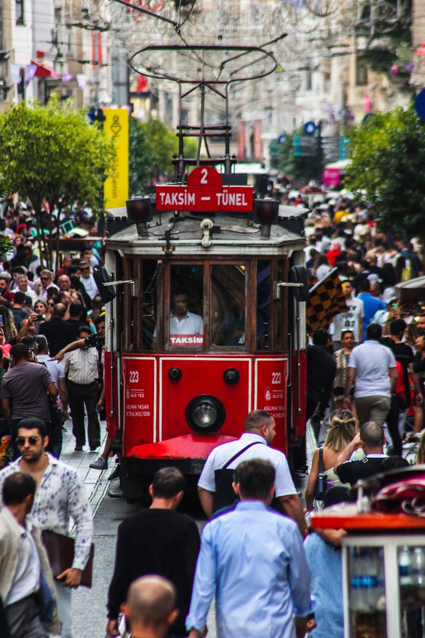 a moving tramway surrounded by people walking on the street of a city