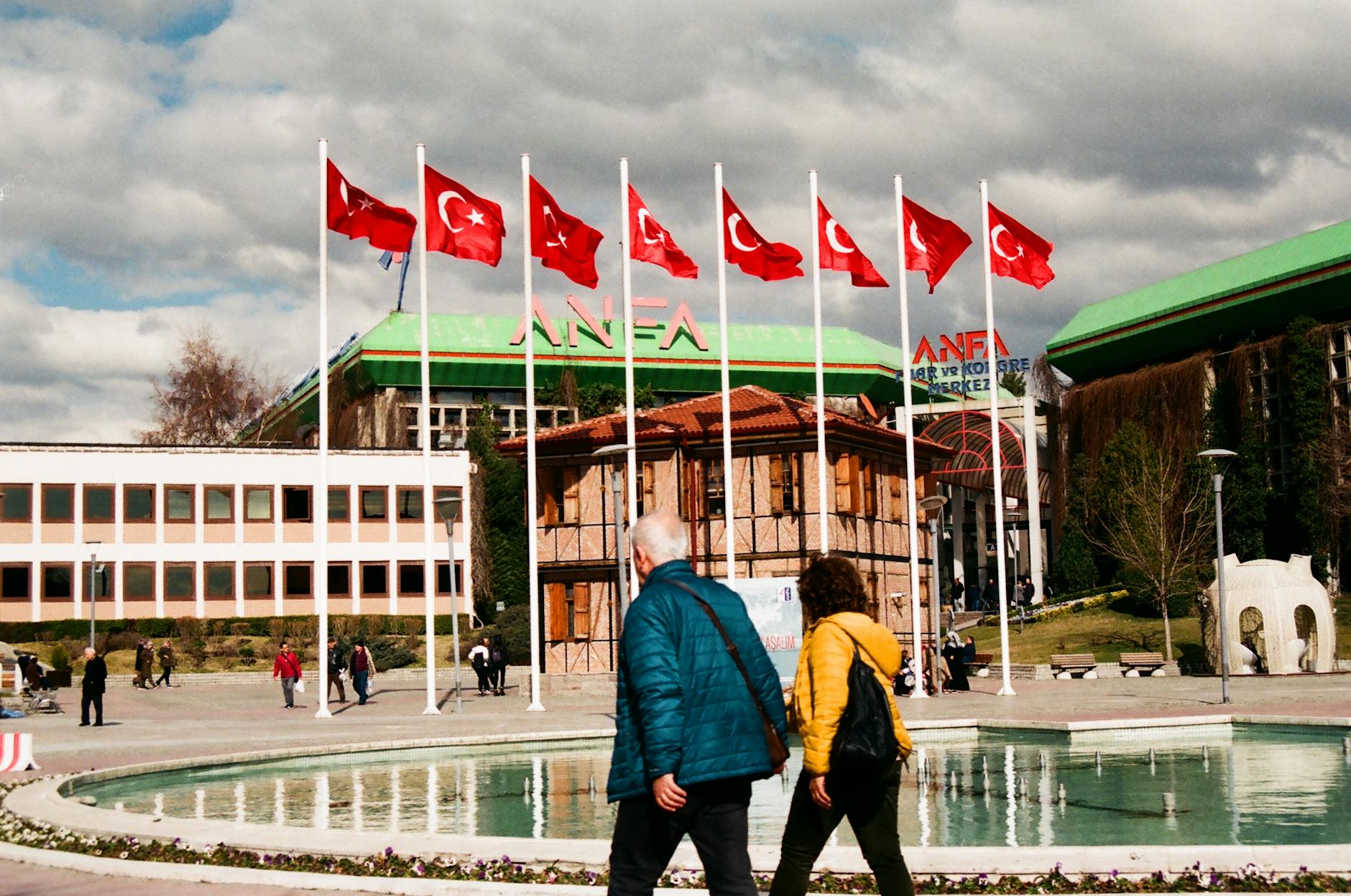 people walking near the water pond with flags