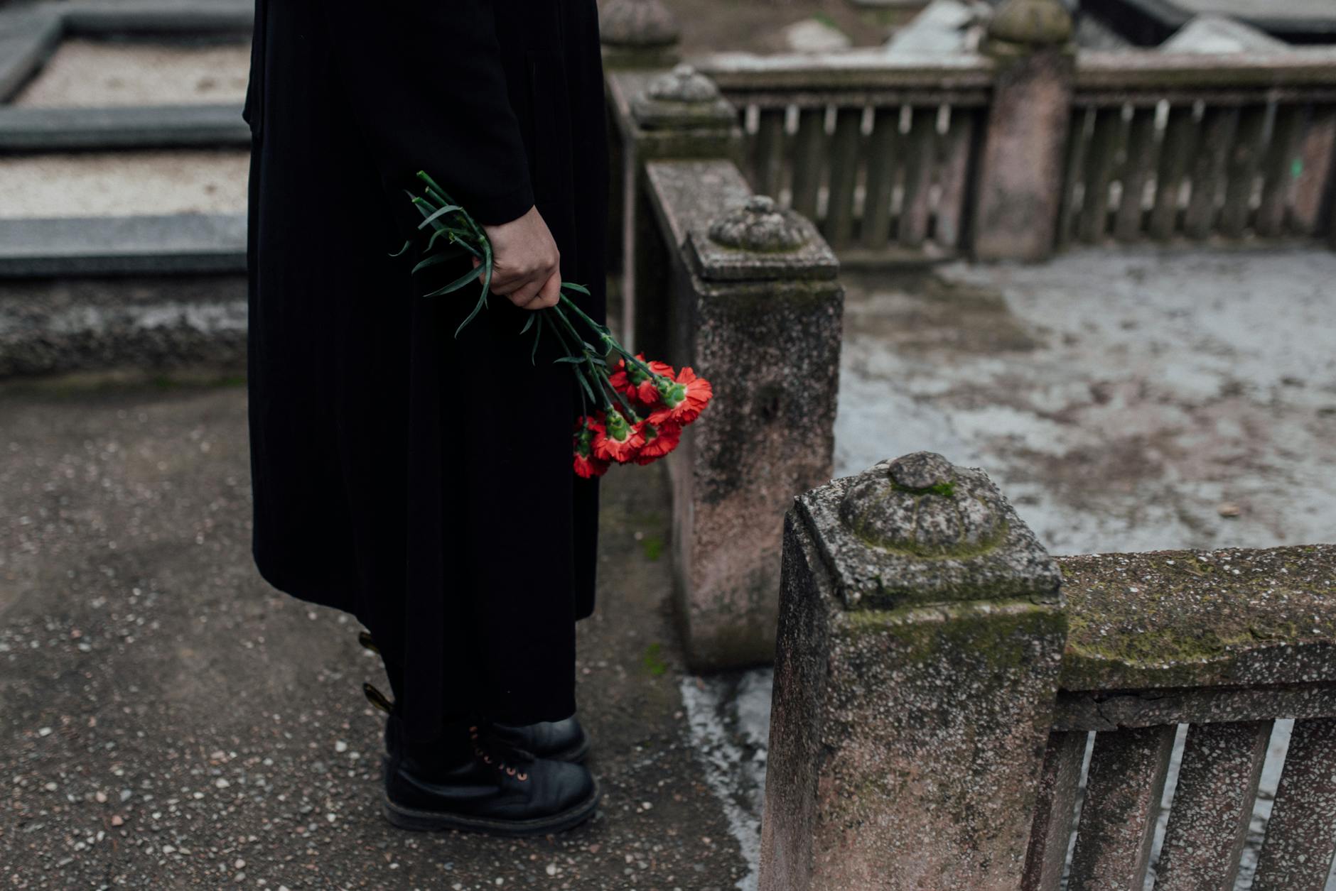 person in black long sleeve dress holding red flowers